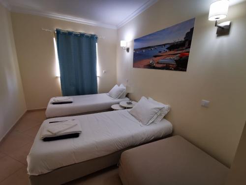 a hotel room with two beds and a window at Cabanas Family Apartment in Cabanas de Tavira