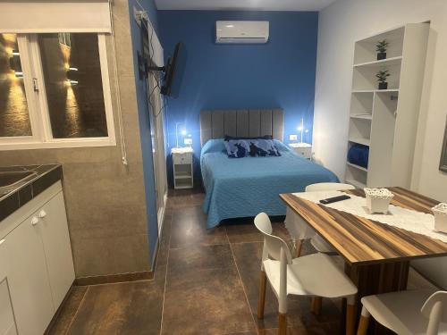 a bedroom with a bed and a table and a kitchen at Aqui es 7 !! in Banfield