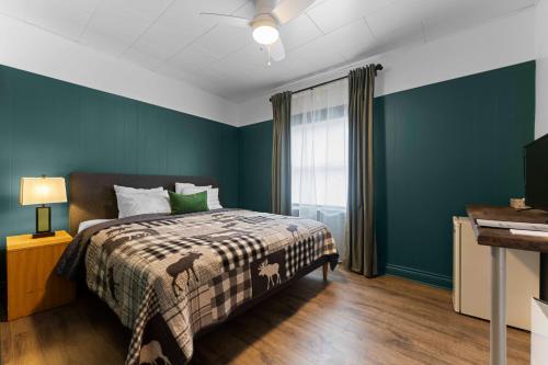 ein Schlafzimmer mit einem Bett, blauen Wänden und einem Fenster in der Unterkunft Balmoral Hotel in Barrys Bay