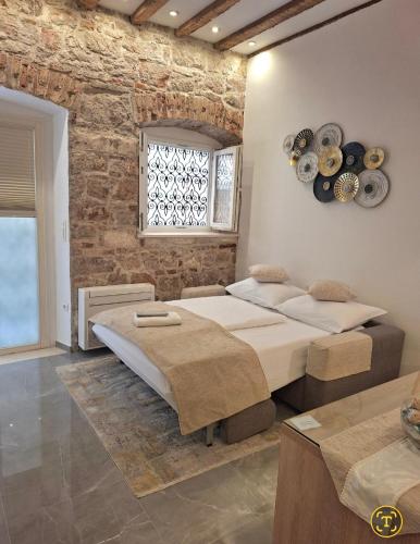 a bedroom with two beds and a brick wall at Dalti Center Apartment in Zadar