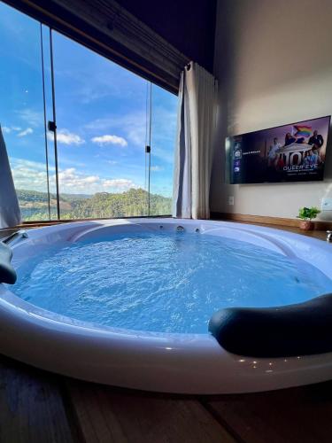 a jacuzzi tub in a room with a tv at Chalé Pazinato in Venda Nova do Imigrante