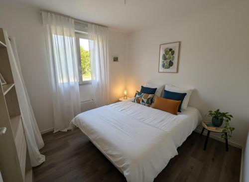 a bedroom with a large white bed and a window at Kougou Ruz in Audierne