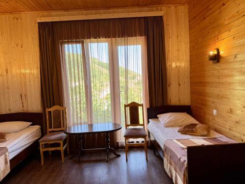 a bedroom with two beds and a table and a window at Кирч Горис in Goris