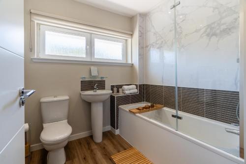 a bathroom with a toilet and a tub and a sink at The Willows in Hurlet