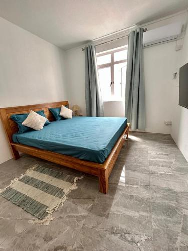 a bedroom with a bed with blue sheets and a window at Serenity villa in Pointe aux Biches