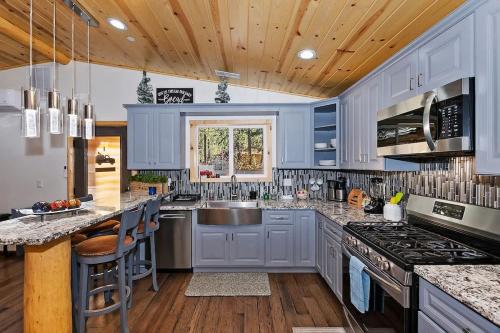 a large kitchen with blue cabinets and a sink at Stylish Elysian Big Bear Cabin w Enclosed backyard in Big Bear City