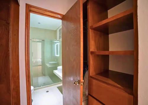 a bathroom with a wooden door and a bathroom with a sink at MRE Goldsmith Polanco in Mexico City