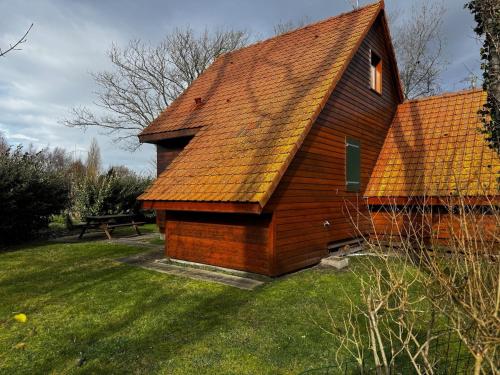 a wooden building with an orange roof on a field at Chalet confortable à Berck-sur-Mer in Berck-sur-Mer