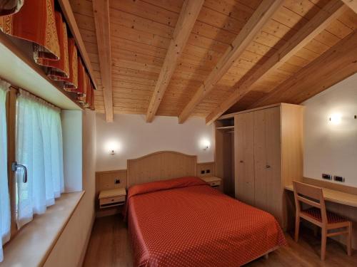 a bedroom with a red bed and a wooden ceiling at Appartamento da Meto in San Martino di Castrozza