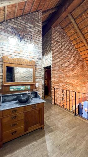 a bathroom with a sink and a brick wall at Sítio Mello in Igrejinha