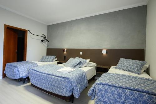 a hotel room with two beds with blue sheets at Hotel Universitario in Itapetininga
