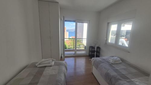 a white room with two beds and a window at Take it slow in Postira