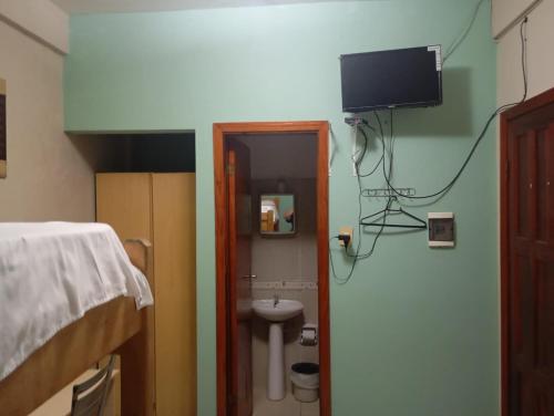 a bedroom with a bed and a sink and a tv on the wall at Marina Hotel in Ciudad del Este