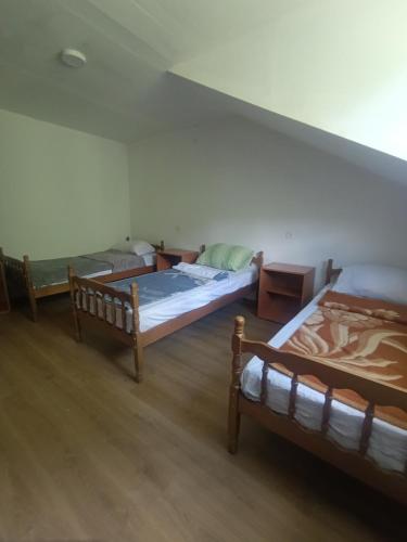 three beds in a room with wooden floors at Anika apartmani in Tjentište