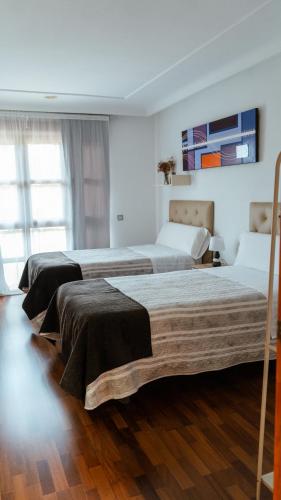 two beds in a room with wooden floors at HOLIDAYS MIRANA in Yecla