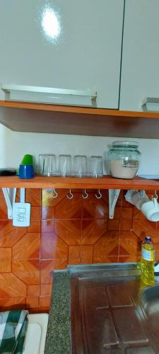 a kitchen with a wooden shelf with glasses on it at Contos de Alice in Tiradentes