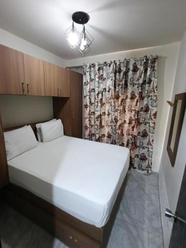 a bedroom with a white bed and a curtain at Taha Yahia Porto Matrouh For Family Only in Marsa Matruh