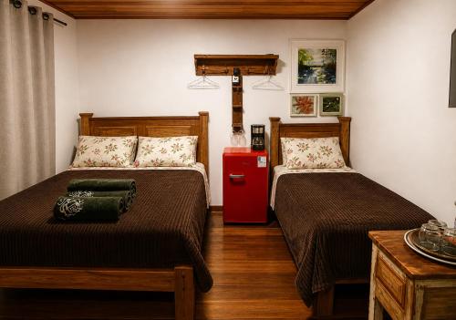 a bedroom with two beds and a red refrigerator at Rio Sereno Suítes Comfort - Lumiar in Lumiar