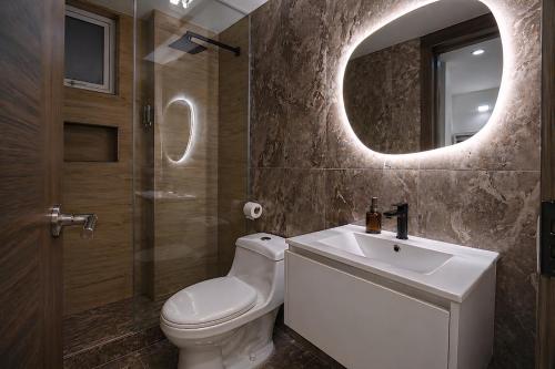 a bathroom with a toilet and a sink and a mirror at CarDiem Suites in Baños