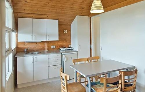 a kitchen with white cabinets and a table and chairs at Lovely Apartment In Farsø in Farsø