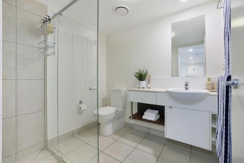 a bathroom with a toilet and a sink and a shower at Dwell @ 22, Oceanfront Apartment in Bargara