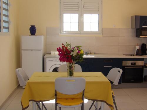 a kitchen with a table with a vase of flowers on it at LAPALOMADESANSEs in Les Anses-dʼArlets