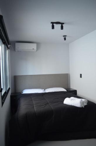 a bedroom with a black bed with white pillows at BoxPoint MotoResort in Córdoba