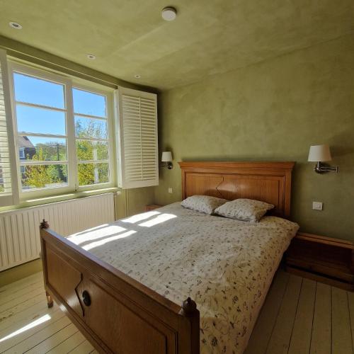 a bedroom with a bed and two windows at Authentiek Vakantiehuis Bos-en-Veld - Prive-tuin - Fietsvriendelijk vlakbij Brugge in Wingene