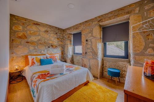a bedroom with a stone wall with a bed in it at Os Paizinhos do Arrujo in Cinfães