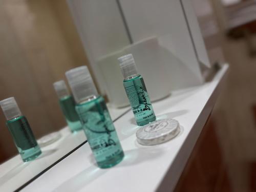 a bathroom counter with three bottles of soap and a mirror at Готель «У Батька» in Truskavets