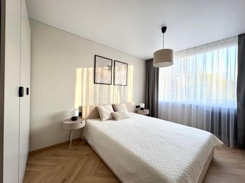 a white bedroom with a bed and a window at Work & Stay Apartment Klaipėda in Klaipėda