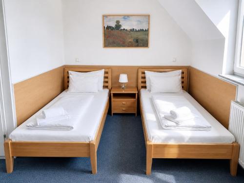 two beds in a small room with a night stand at Hotel Donaustadt Kagran - at Metro U1 in Vienna