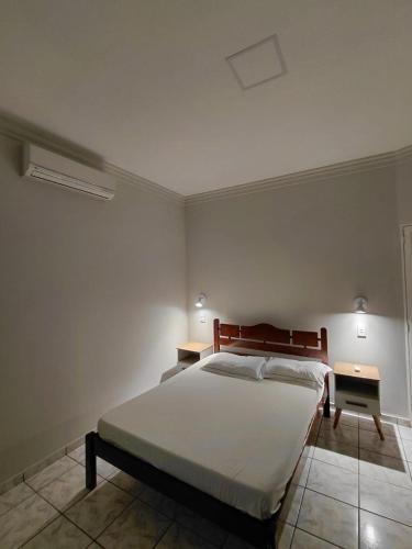 a bedroom with a large bed and a night stand at Nosso Lar casa inteira, completa e independente in Barra do Garças