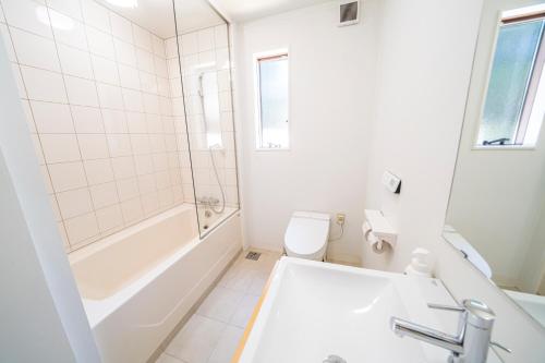 a bathroom with a tub and a toilet and a sink at Alps Retreat Chalet by Morino in Hakuba