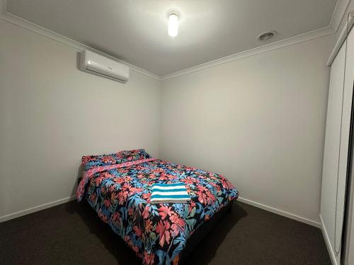 ein kleines Schlafzimmer mit einem Bett mit einer bunten Bettdecke in der Unterkunft Your Guest House in Tarneit