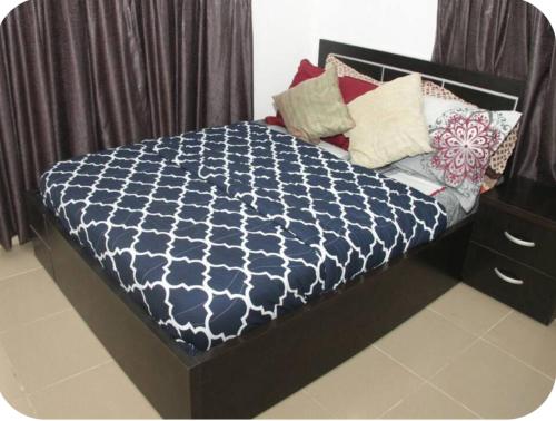 a bed with a blue and white comforter and pillows at Kadosh Homes - 2Bed Apartment in Magboro