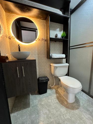 a bathroom with a toilet and a sink and a mirror at Finca Hotel Cabaña Fercho in Quimbaya