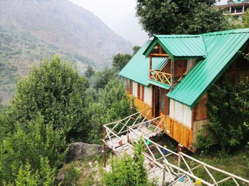 a house with a green roof on a mountain at Himalayan Abode Tree House in Sainj