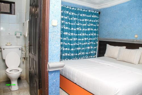 a small bedroom with a bed and a toilet at DeBoss Hotel in Ikeja