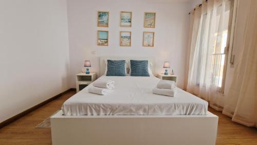 a white bed in a white room with a window at Island Dream Apartment in Olhão