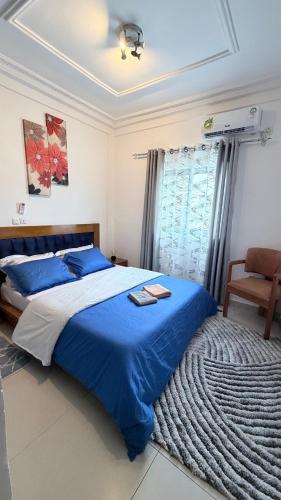 a bedroom with a large bed with a blue blanket at Eva Apparts "situé à Kotto Baden Baden" - PARKING CAMERA BALCON WIFI CLIM CONFORT in Douala