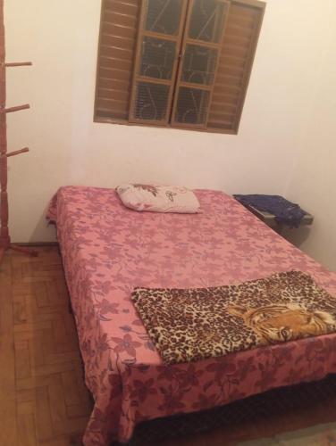 a bedroom with a bed with a red bedspread at Pousada May in Ribeirão Preto