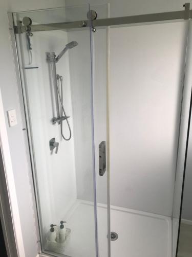 a shower with a glass door in a bathroom at Cosy Beach House in Riverton