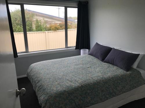 a bedroom with a bed and a large window at Cosy Beach House in Riverton