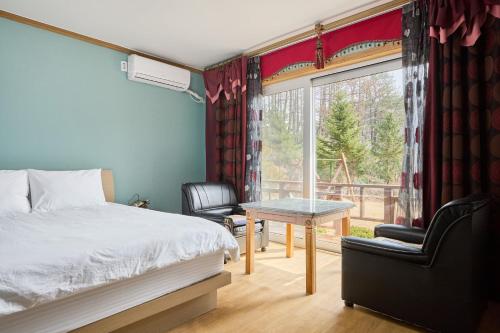 a bedroom with a bed and a table and a window at Heidi Korea in Hongcheon