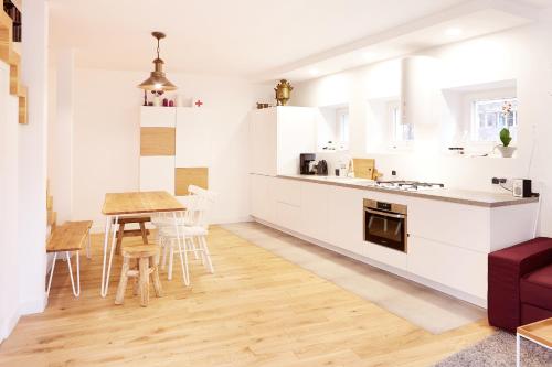 a kitchen with white cabinets and a table and chairs at Lovely LUX Garden Flat near Royal Park in Warsaw