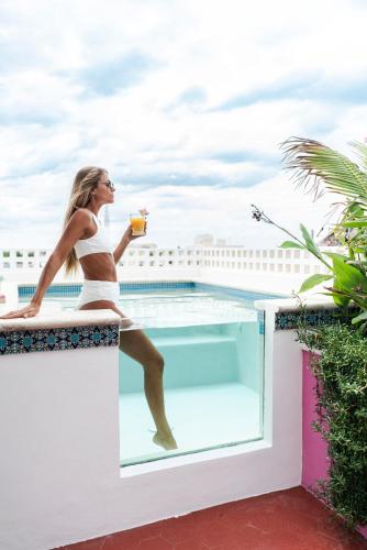 a woman in a bikini sitting on a balcony with a drink at Casa Bene Villas in Isla Mujeres