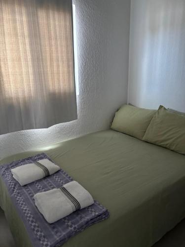 a bed with two pillows on it with a window at Casa Cielo y Noche in Ahuachapán
