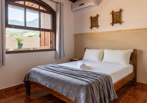 a bed in a room with a window and a bedspread at Cantinho no litoral a 100mts da praia in São Sebastião