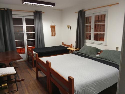 a bedroom with two beds and a table and windows at Hospedaje por 7 días 15 dias o Mes in La Serena